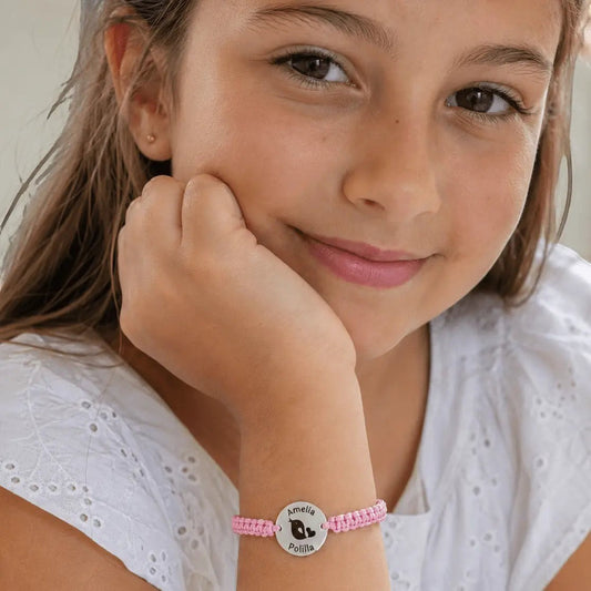Pulsera Moment de cordón rosa ajustable con medalla de plata personalizada con nombre y dibujo en la muñeca de una niña