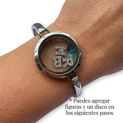 Brazalete Moment de acero quirúrgico con medallón circular de vidrio que contiene figuras personalizadas en la muñeca