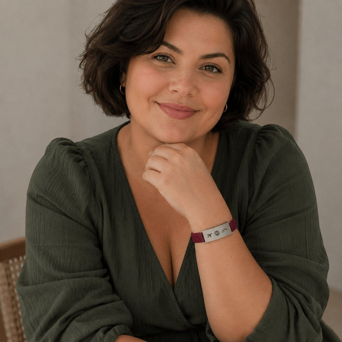 Mujer sonriente luciendo un brazalete Flex personalizado de Moment con placa de acero inoxidable y cordón elástico burdeos