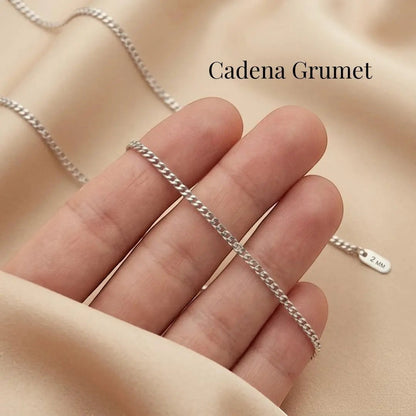 Cadena grumet plateada de acero quirúrgico de Moment sostenida en la mano sobre fondo de tela beige suave