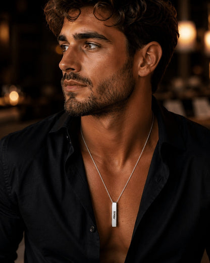 Collar con barra personalizada de Moment en acero inoxidable, lucido por un hombre con camisa negra abierta.
