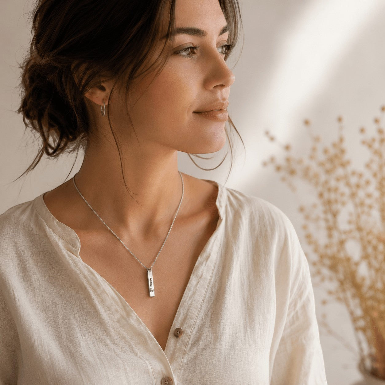 Mujer luciendo un collar con barra grabada personalizada de acero inoxidable de Moment, estilo minimalista y elegante.