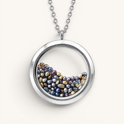 Collar Moment Océano con medallón circular de acero quirúrgico y vidrio relleno de pequeñas gemas en tonos azules y oro
