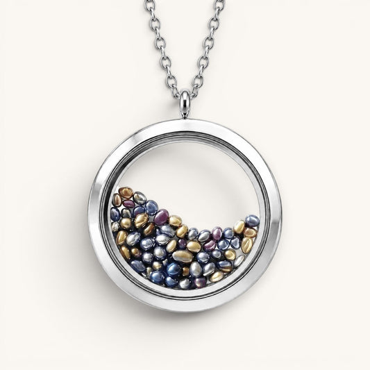 Collar Moment Océano con medallón circular de acero quirúrgico y vidrio relleno de pequeñas gemas en tonos azules y oro