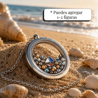 Collar Moment Océano con medallón de acero y vidrio lleno de pequeñas gemas metálicas sobre arena de playa