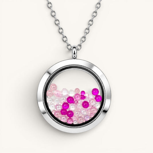 Collar Moment con medallón circular de acero y vidrio lleno de pequeñas esferas rosadas y blancas