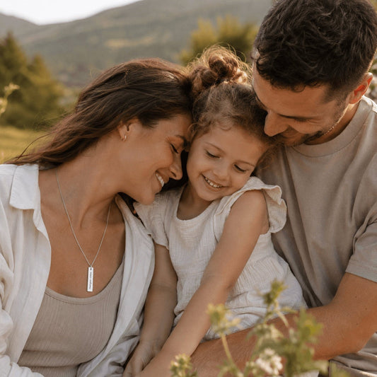 Mujer sonriente con collar Moment de placa rectangular vertical personalizada de acero inoxidable junto a su familia