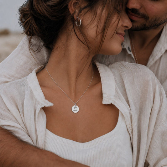 Collar Moment de plata con medalla redonda personalizada grabado con texto, lucido por una mujer en un abrazo romántico