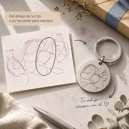 Llavero Moment de acero inoxidable plateado con el dibujo de un niño grabado, presentado junto a una nota de regalo.