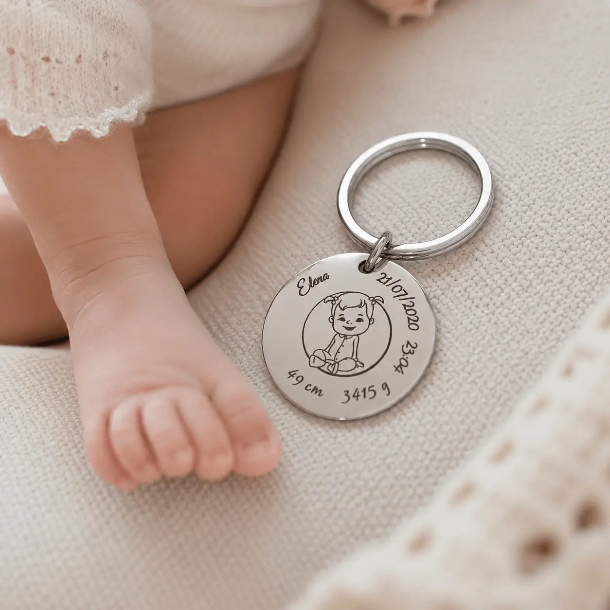 Llavero Moment de acero inoxidable plateado con grabado personalizado de nacimiento junto al pie de un bebé