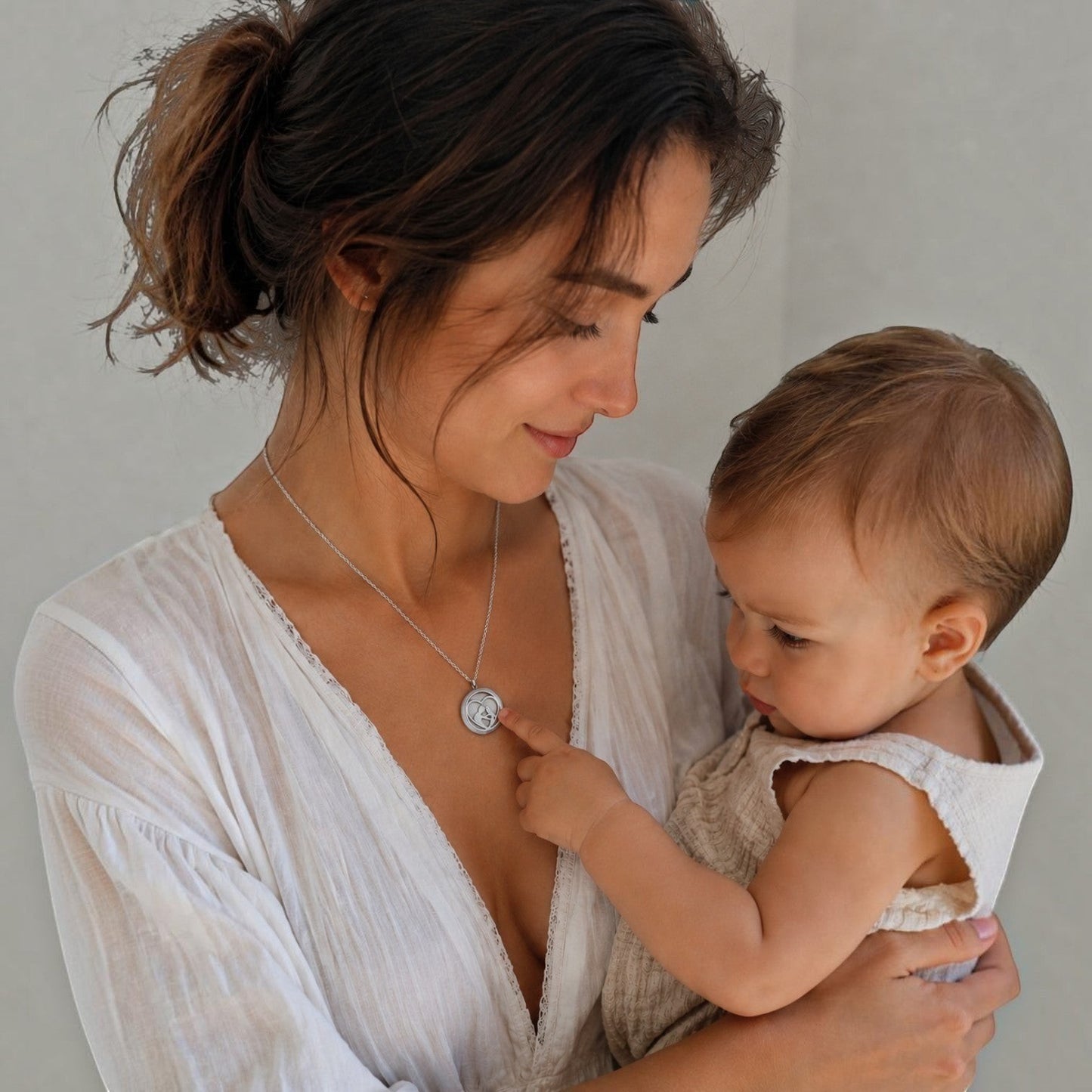 Mujer con bebé usando collar medallón perfumado Moment de acero inoxidable con diseño amor de mamá