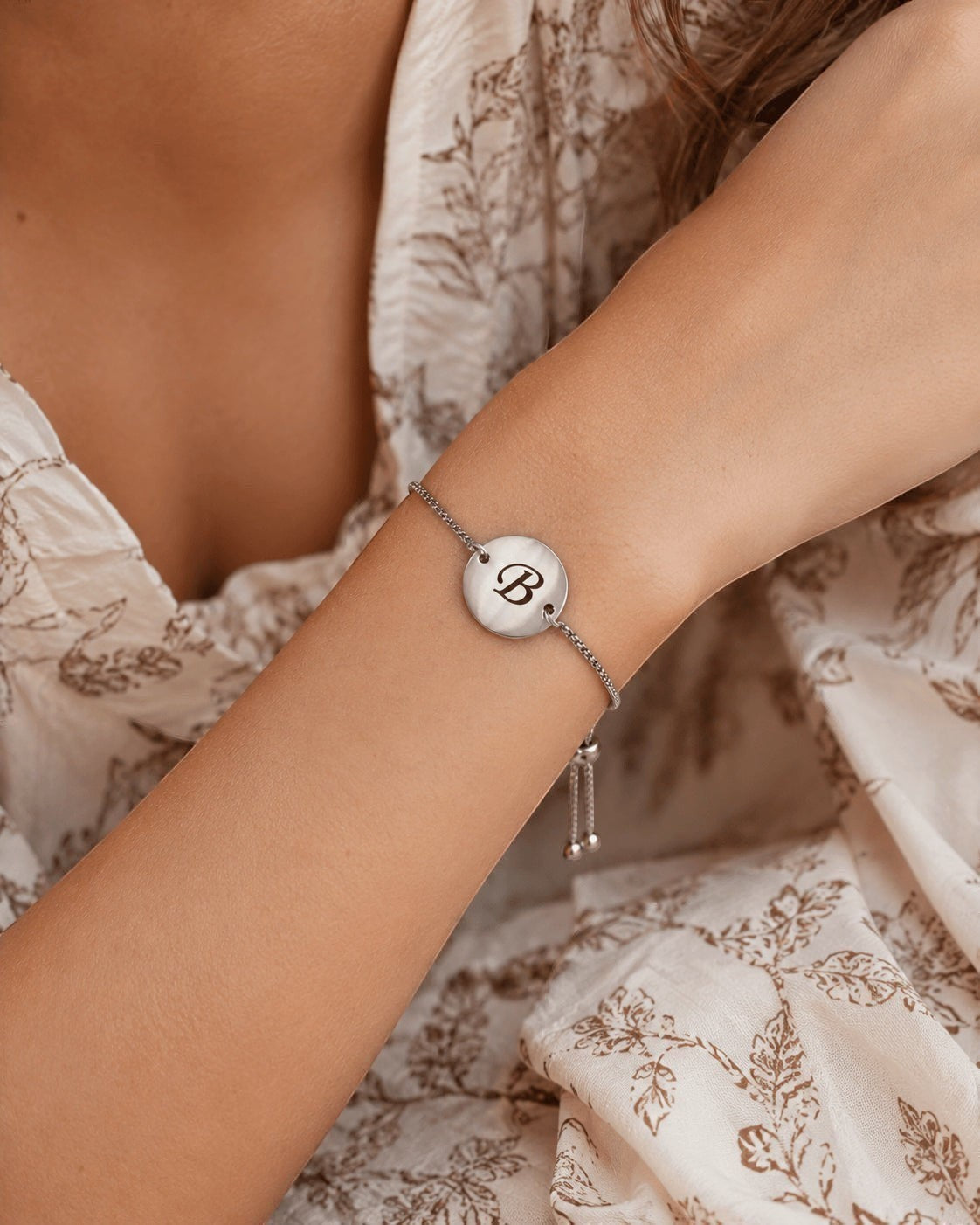 Pulsera Aura personalizada de Moment en acero inoxidable con medalla grabada con la letra B en una muñeca